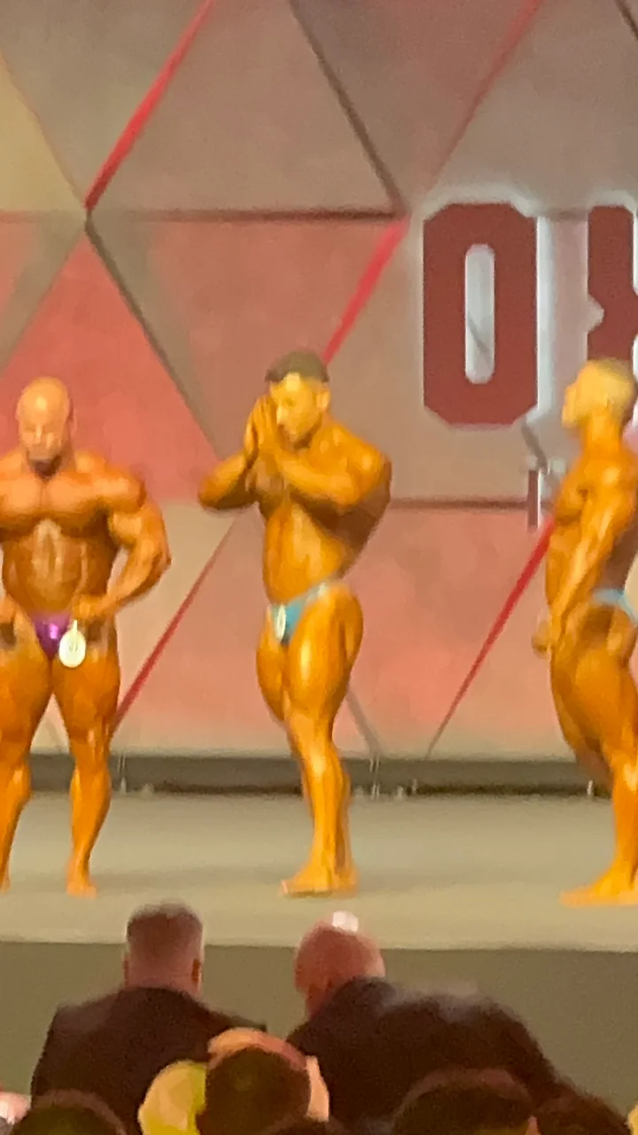 A closer, softly focused view of competitors posing on the Dubai Pro stage in 2025