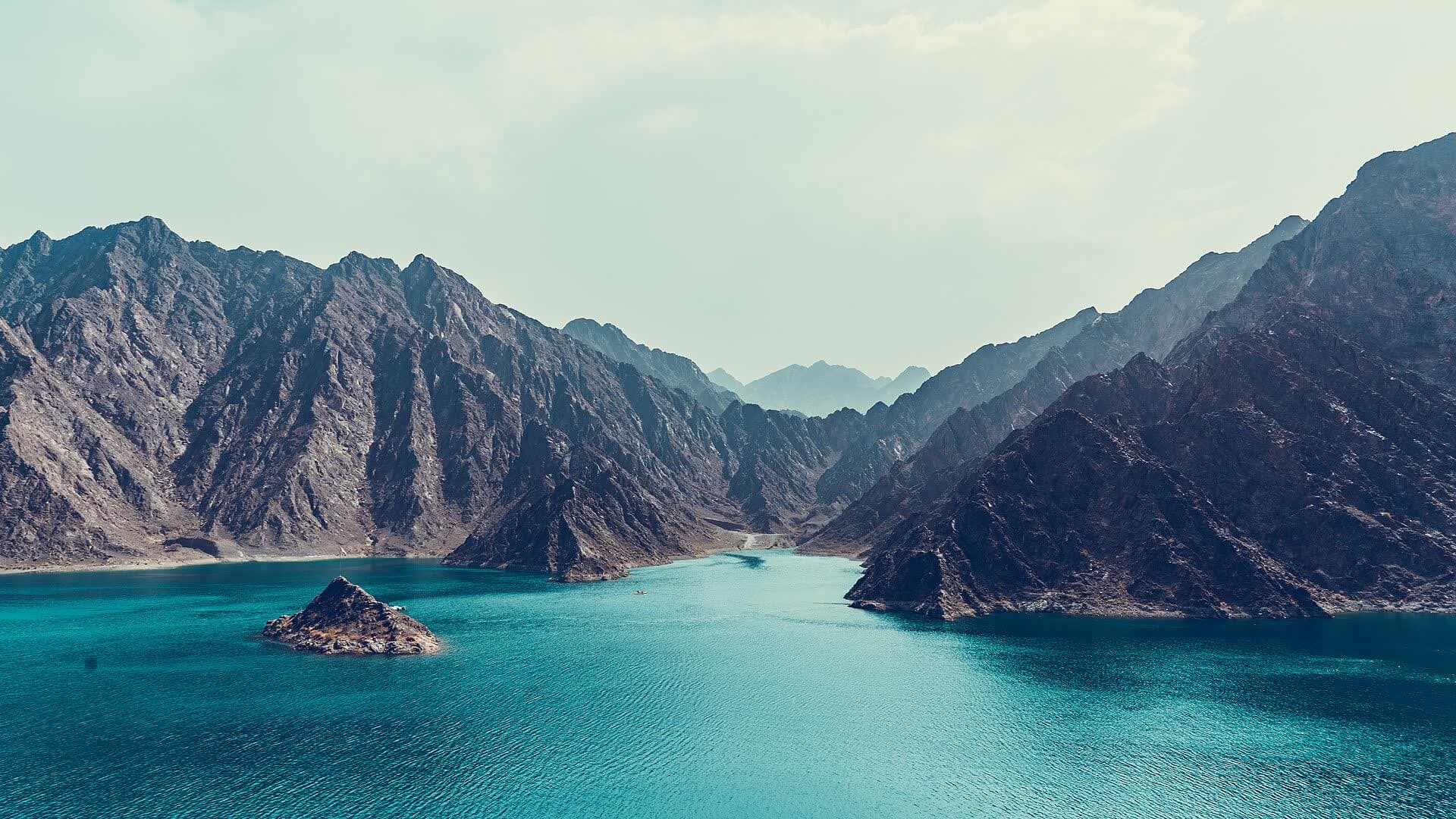A wider look across Hatta's reservoir and mountain ridges. Water levels and the appearance of the landscape vary.