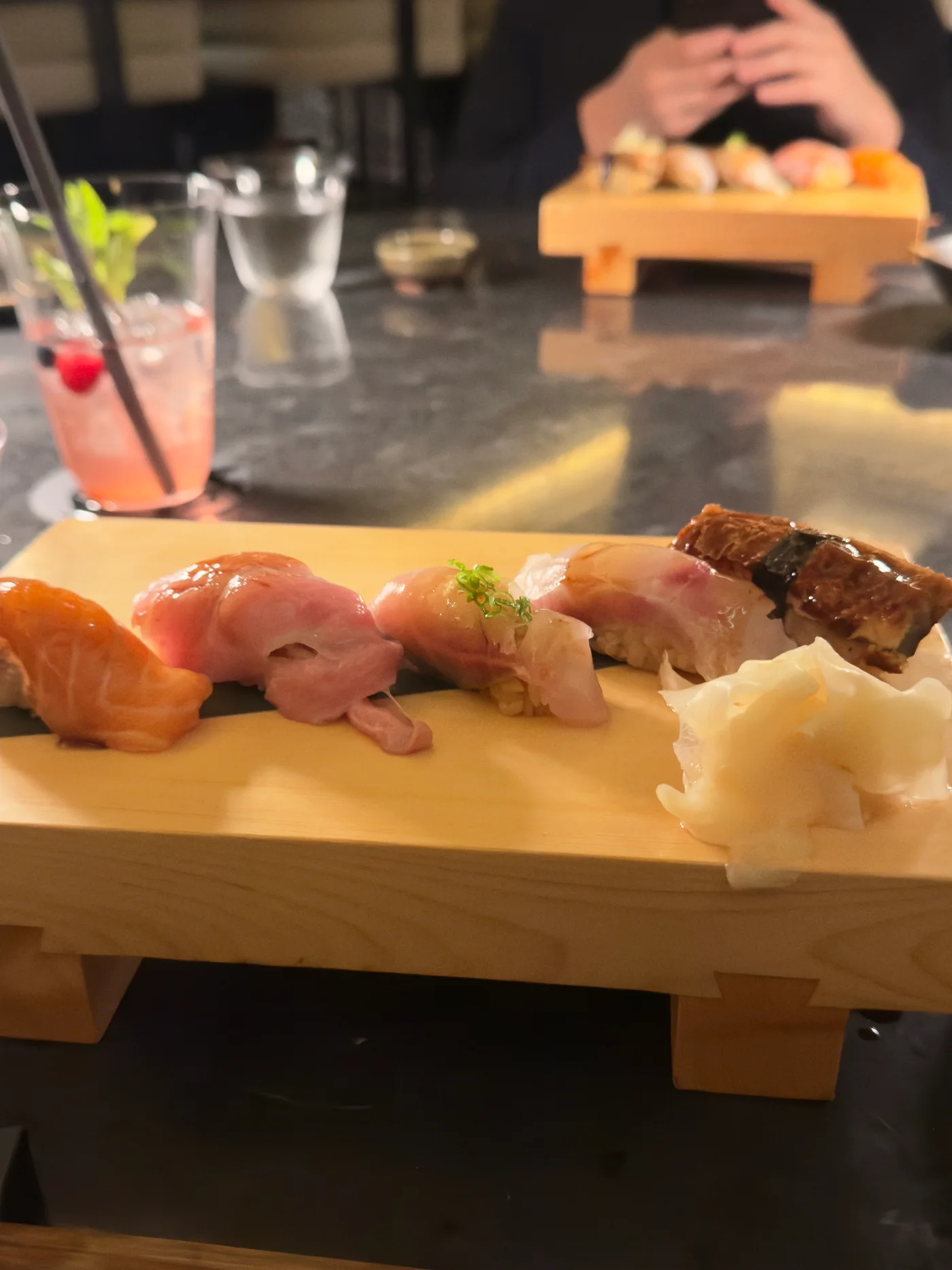 Nigiri sushi on a wooden serving stand during an evening visit to Kasumigaseki