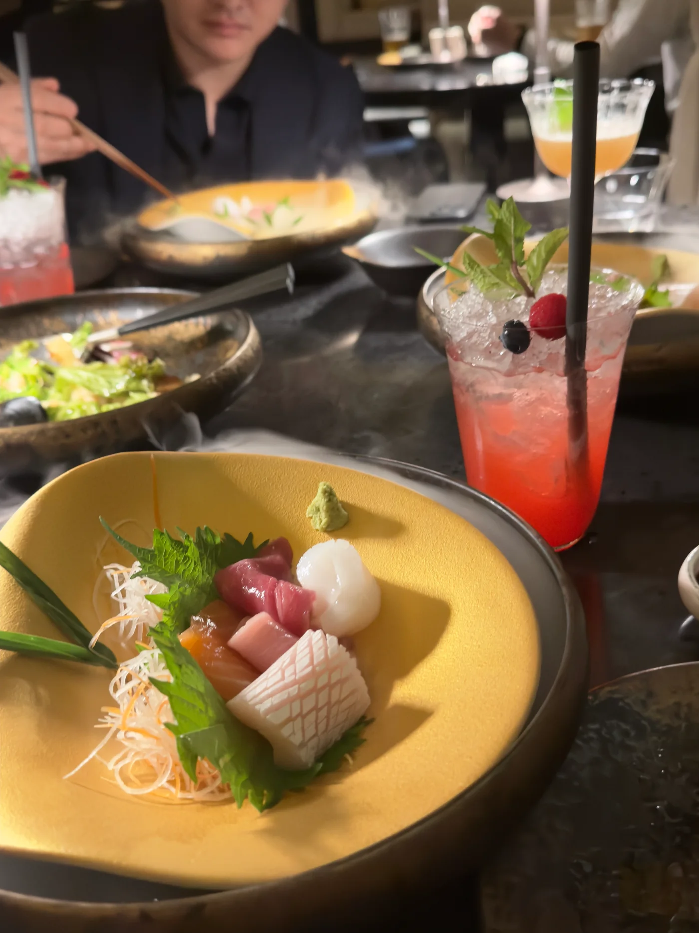 Sliced fish, drinks and other dishes arranged across a dining table at Kasumigaseki
