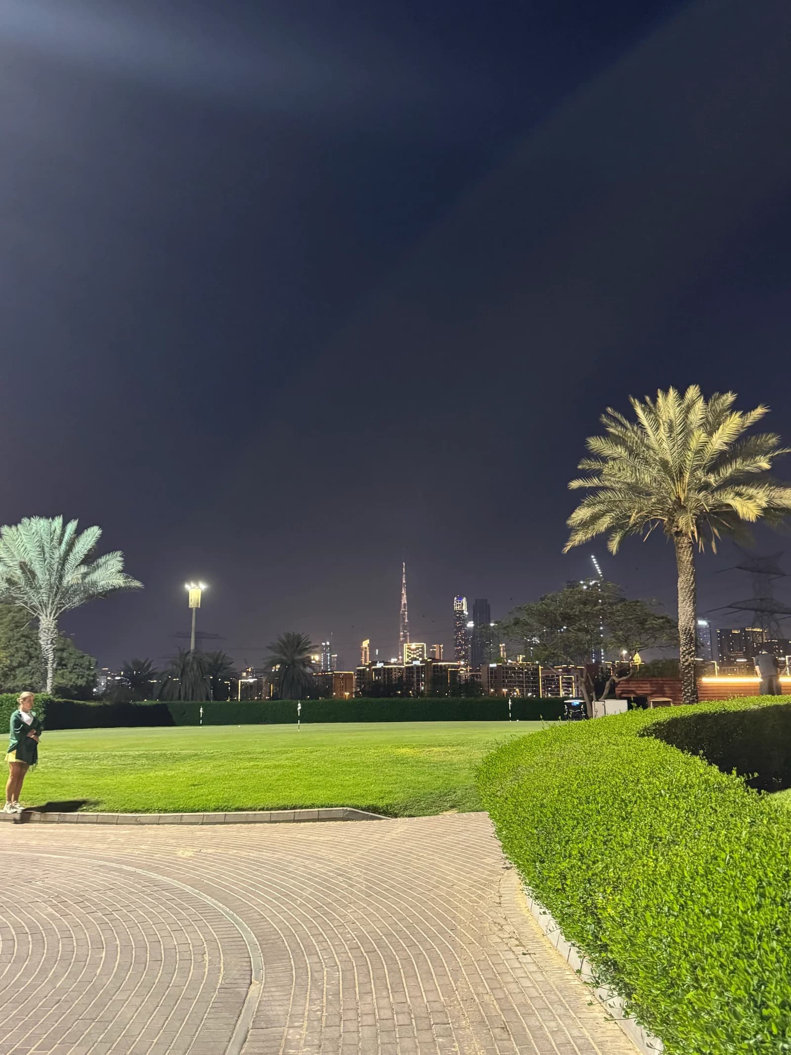 Palm-lined practice green at Meydan with the illuminated Burj Khalifa in the distance