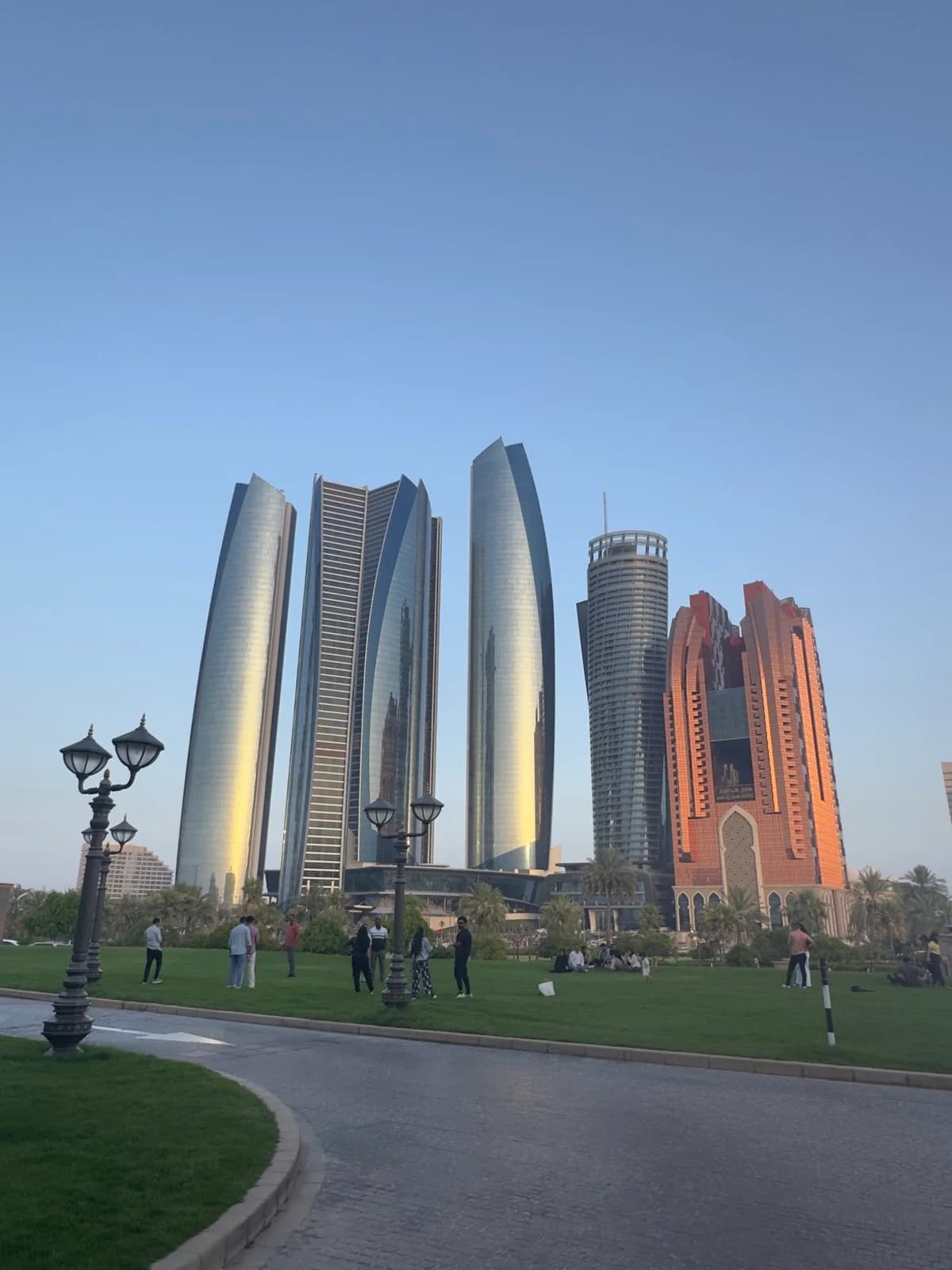 Abu Dhabi towers beyond a waterfront lawn and walking path